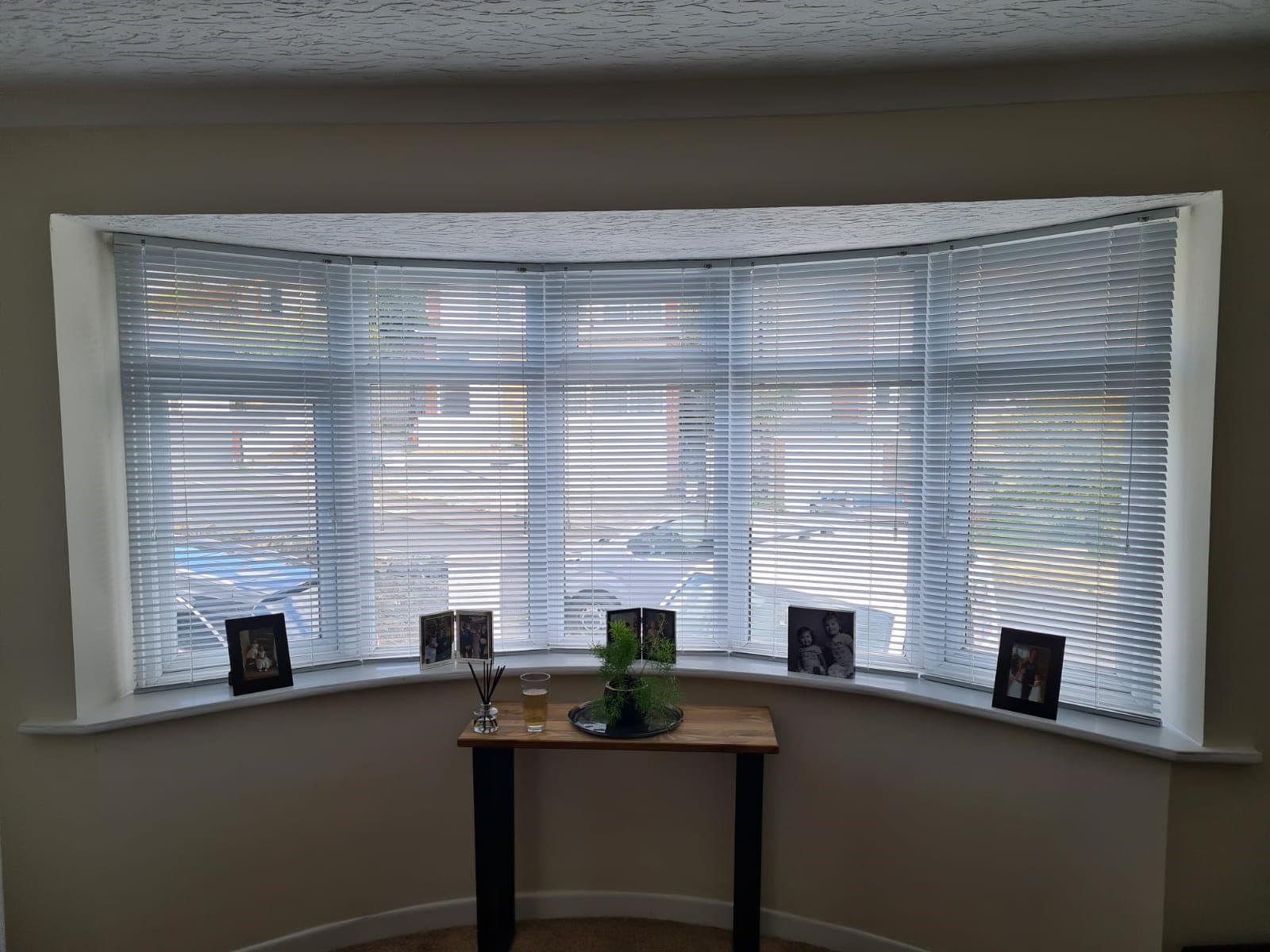 White venetian blinds closed behind a sink in a white and gray marble kitchen