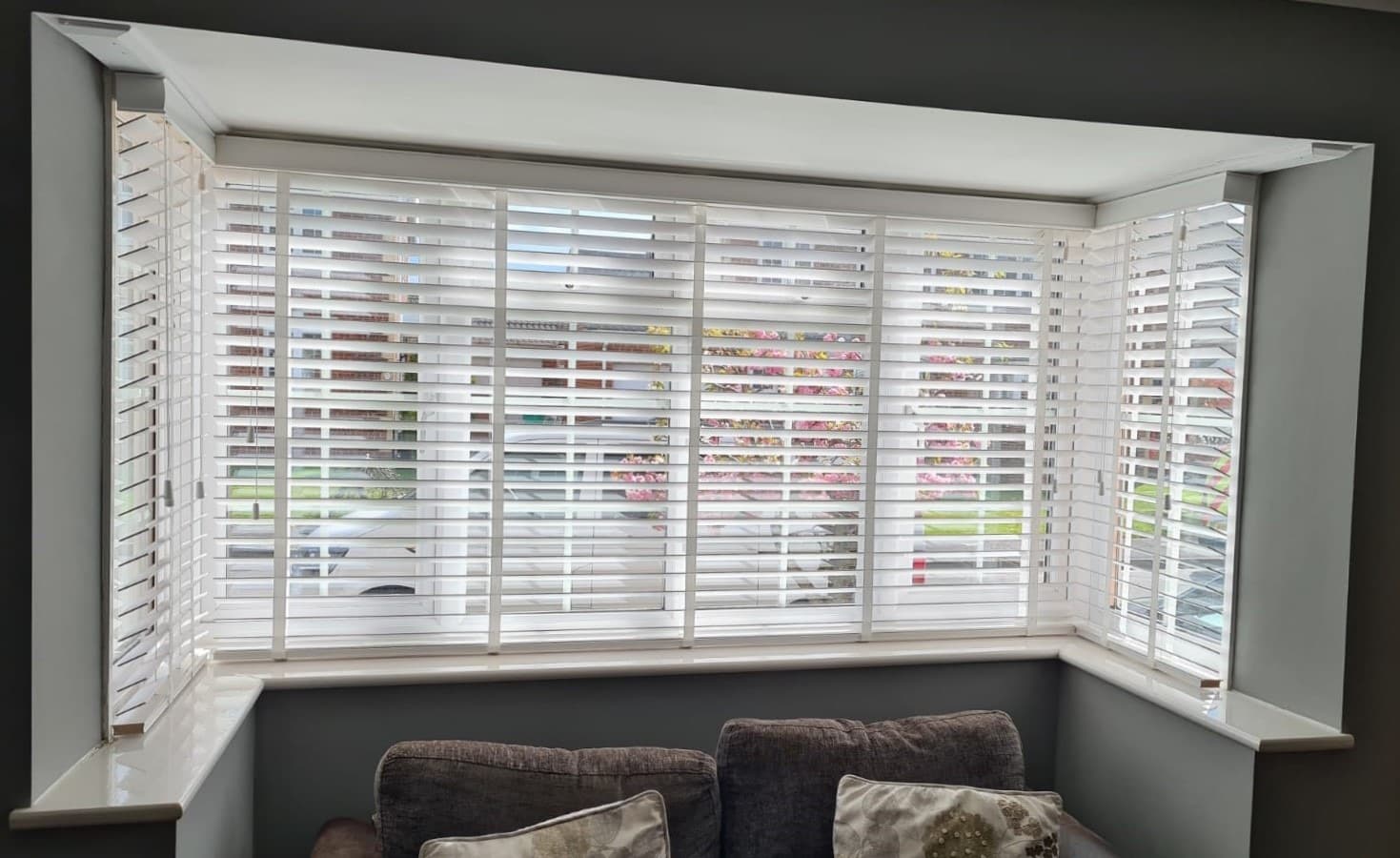 White venetian blinds closed behind a sink in a white and gray marble kitchen