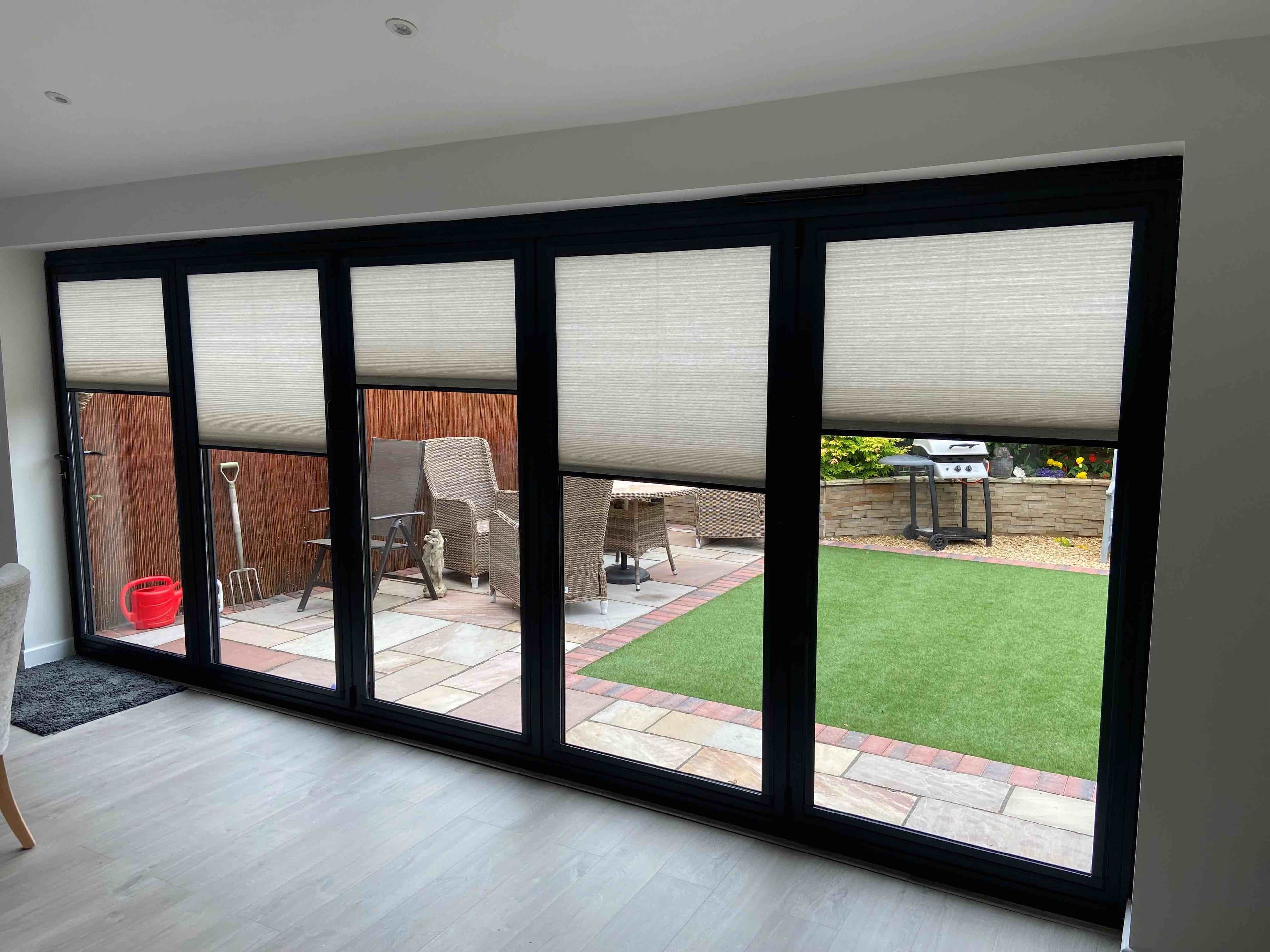 Pink perfect fit blinds in a white bedroom with wooden beamns and white exposed brickwork